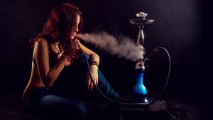 Red-haired girl sitting smoking a hookah. Girl enjoying exhales.